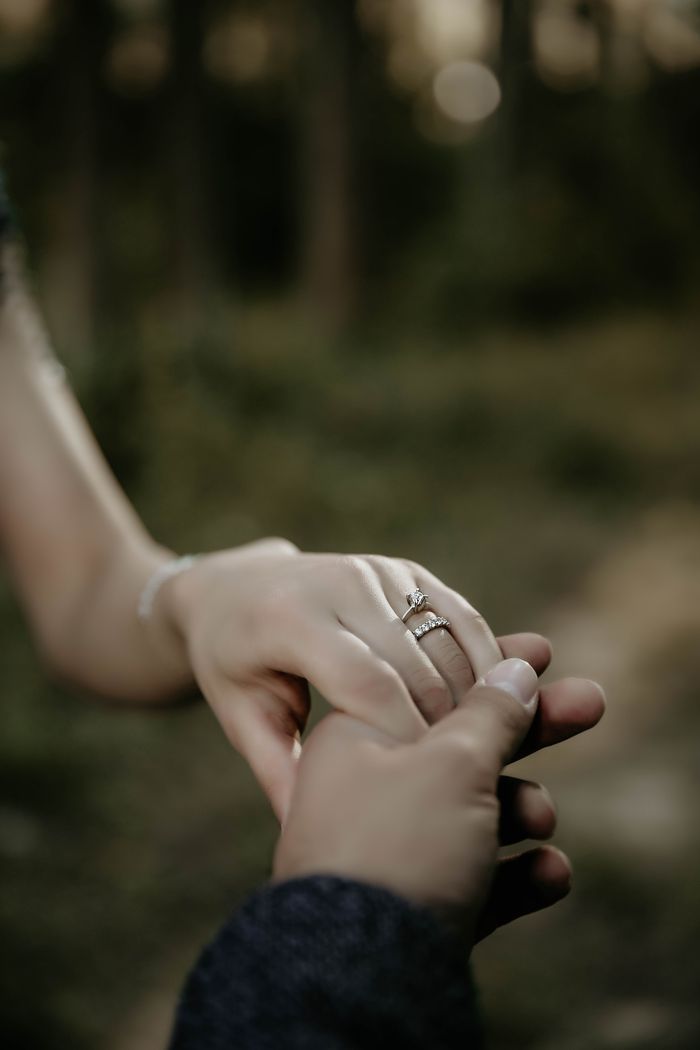 Close-up of a couple holding hands with a focus on a diamond ring, symbolizing love.