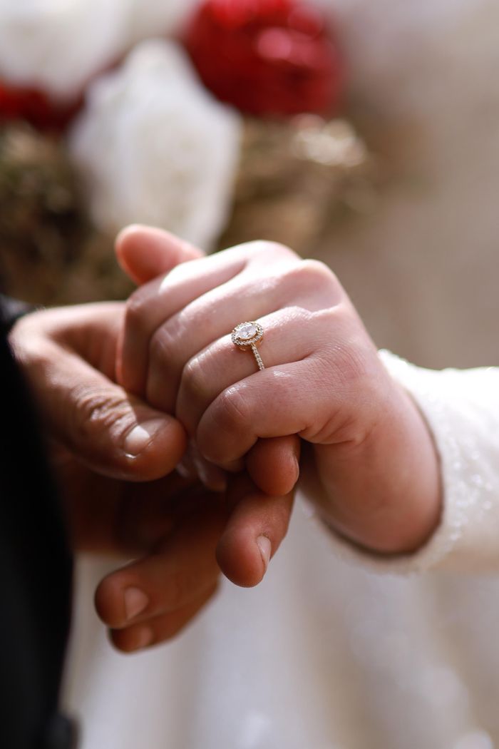 Close-up of a couple holding hands, showcasing an elegant engagement ring, symbolizing love and commitment.