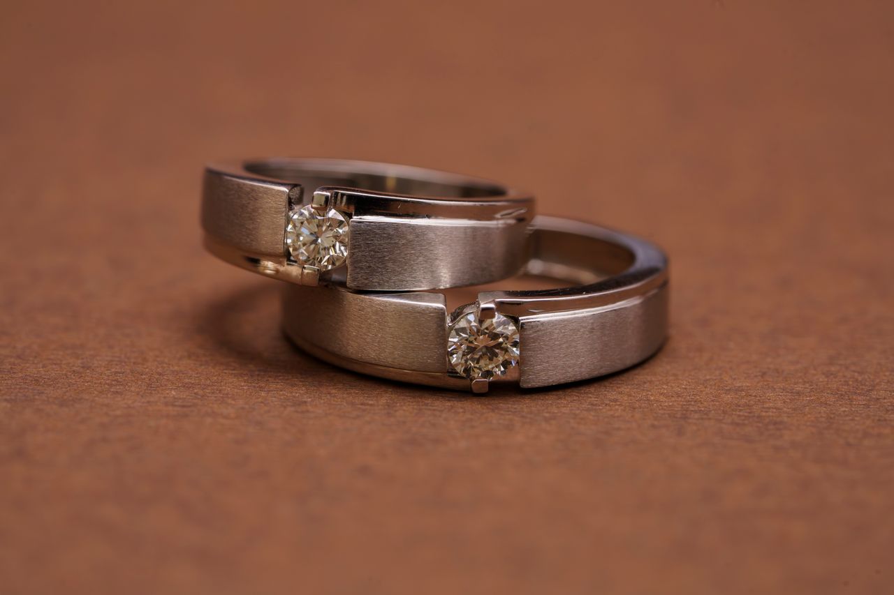 Close-up of two elegant diamond wedding rings on a textured brown surface, symbolizing love and commitment.
